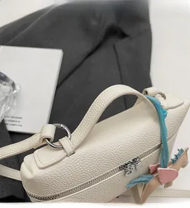 Dettaglio della borsa in pelle litchi bianco crema con ciondolo a cavallo tricolore e anelli a D