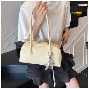 Gros plan du sac Boston crème avec pendentif étoile sur un fond d'escalier intérieur