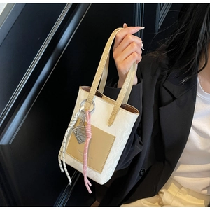Vue détaillée du mini sac cabas crème avec poche marron et breloque raquette de tennis