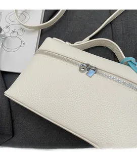 Dettaglio della pelle a grana di ciottoli bianco crema e doppie zip metalliche della borsa