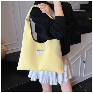 Detail of minimalist yellow velvet tote bag with woven label shown on female model