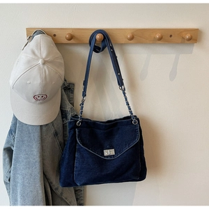 Close-up of deep blue denim shoulder bag with silver twist lock and metal chain strap