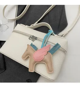 Dettaglio borsa bianca in pelle litchi con ciondolo a forma di pegaso colorato