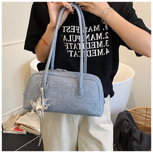 Détail du sac Boston bleu clair texturé avec breloque étoile argentée et anses longues
