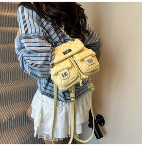 Macro detail of a light yellow quilted mini backpack with metallic turn-lock closures