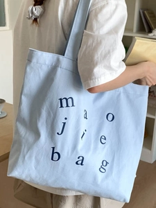 Light blue canvas tote bag with letter print shown from a side view on a model