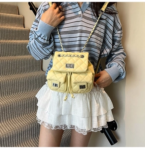 Detail of yellow quilted mini backpack with metal chain straps and twist-lock pockets