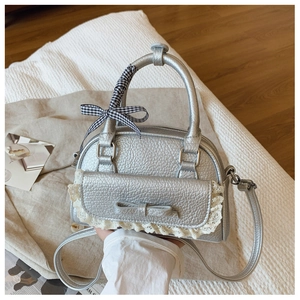 Detail of silver shell bag with lychee texture, lace trim, and plaid ribbon bow