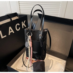 Détail du mini cabas noir gaufré avec pendentif tissé rose et breloque raquette de tennis