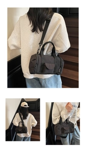 Detail view of a black canvas Boston bag with adjustable strap and side brand label