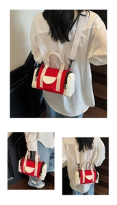 Detail view of a red and off-white canvas barrel bag featuring side zippers and adjustable strap
