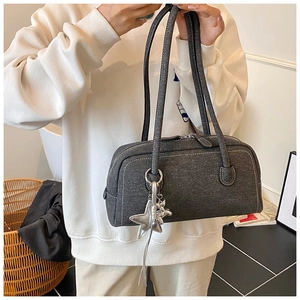 Gros plan du sac Boston gris foncé avec texture en tissu et breloques de chien en argent