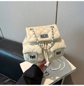 Detail of cream quilted mini backpack featuring silver twist-locks and chain handles