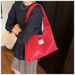 Detailed view of red velvet tote bag showing high-gloss texture and brand logo tag