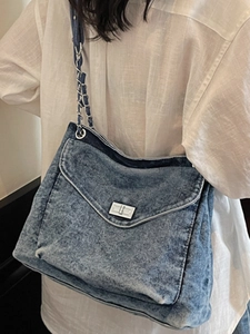 Denim shoulder bag with silver chain strap and rectangular turn-lock in street style