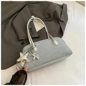 Détail d'un sac Boston gris argenté avec breloque étoile et chien ballon sur veste