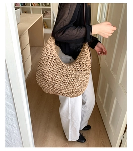 Detail of hand-woven straw hobo bag with deep brown shoulder strap and textured weave