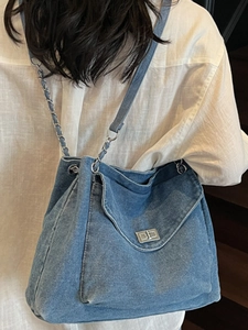 Classic blue denim shoulder bag with chain strap and silver twist lock on female model