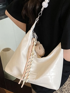 Off-white crocodile pattern shoulder bag with pearl strap and tassel detail on model