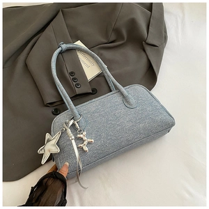 Détail du sac Boston en denim bleu clair avec breloques étoile et chien ballon sur un costume