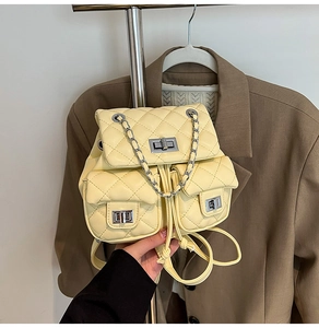 Detail of yellow quilted backpack with silver twist locks and chain strap on a blazer