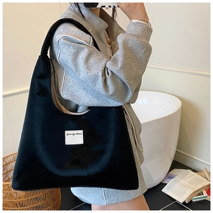 Detailed look at the black velvet tote bag showing the white label and wide shoulder strap