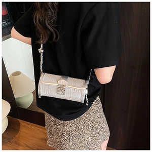 Close-up of silver sequin cylinder bag featuring metallic M clasp and elegant chain strap