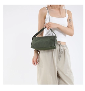Detail of dark green canvas shoulder bag with silver chain and wide strap on model