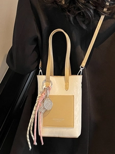 Petit sac carré vintage crème et jaune avec pendentif raquette sur une veste noire