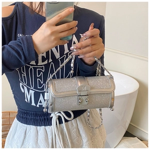 Detail of silver cylinder bag with glitter texture and metallic letter M buckle clasp