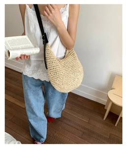 Detail of hand-woven straw hobo bag showing beige texture and black leather strap