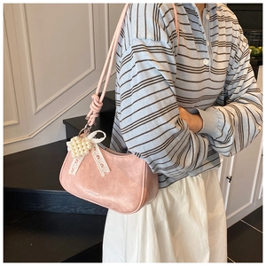Pink faux leather shoulder bag with pearl strap and lace bow charm detail view