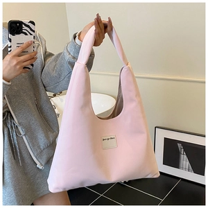 Macro detail of the light pink velvet fabric and branded label on the minimalist tote bag