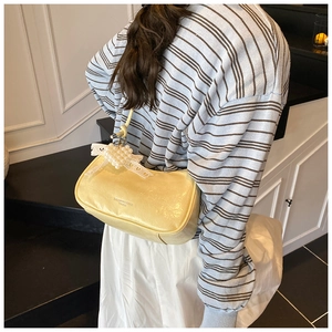 Detail of pale yellow crossbody bag with pearl heart charm and bow on the shoulder strap