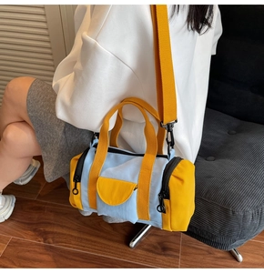 Detail of color-block Boston barrel bag featuring light blue canvas and yellow strap
