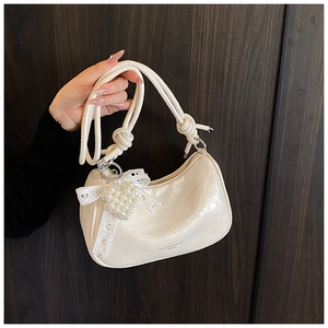 Detail of cream white pleated bag with woven handles, pearl heart, and lace bow decor