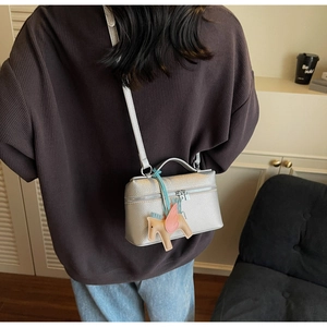 Dettaglio della mini borsa a scatola argento con motivo litchi e ciondolo a cavallo