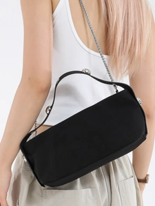 Modern black cylinder underarm bag with silver studs and chain strap on a model
