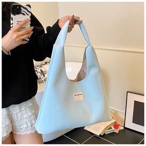 Close-up of light blue velvet tote bag showing the soft texture and leather logo patch