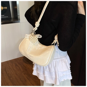 Detail of cream cloud bag featuring lace bow, pearl heart and woven shoulder strap