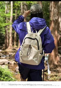 Outdoor shot of cream nylon backpack with drawstrings on model in forest setting