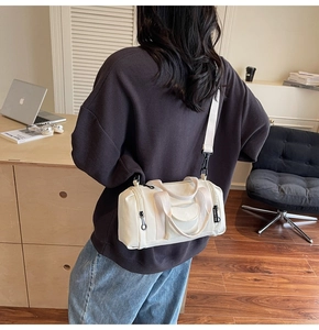 Detailed view of cream canvas boston bag with black zipper and branded fabric label