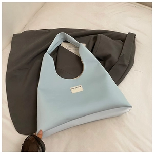 Detail view of a light blue PU leather tote bag with brand label and spacious interior