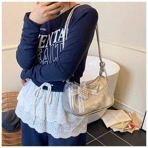 Detail of silver metallic cloud bag featuring lace bow and pearl decoration with a knot strap