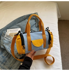 Detail of color-block canvas Boston bag with dual handles and webbing strap on white bedding