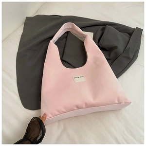 Detailed view of pink nylon tote bag with minimalist logo patch on soft fabric