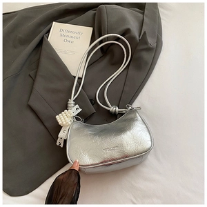 Detail of silver metallic hobo bag featuring lace pearl charm and fashion branding