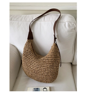 Detail view of woven hobo bag with dark brown leather strap on a white surface