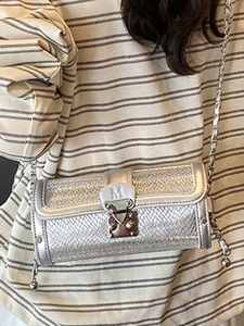 Silver cylinder chain crossbody bag featuring a metal M-logo buckle and textured finish