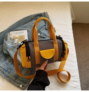 Detail of canvas barrel bag showing yellow and gray contrast color and carry handles